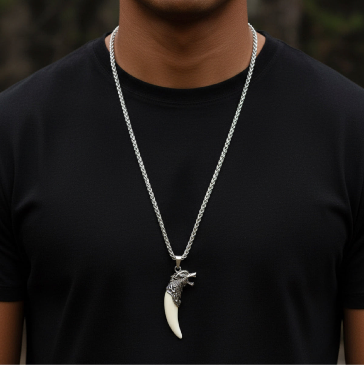 A model in a black T-shirt wearing a silver chain necklace with an ornate wolf-head pendant and cream fang charm.
